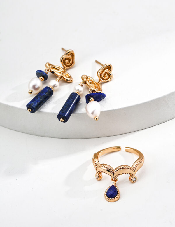 The Oracle’s Whisper Set showcases a harmonious blend of deep blue Lapis Lazuli and vintage gold, featuring the Oracle’s Echo Earrings and Seer’s Vision Ring. The set is designed to empower wearers with wisdom, enhance communication, and provide a sense of serenity, aligning perfectly with the transformative energies of 2025.